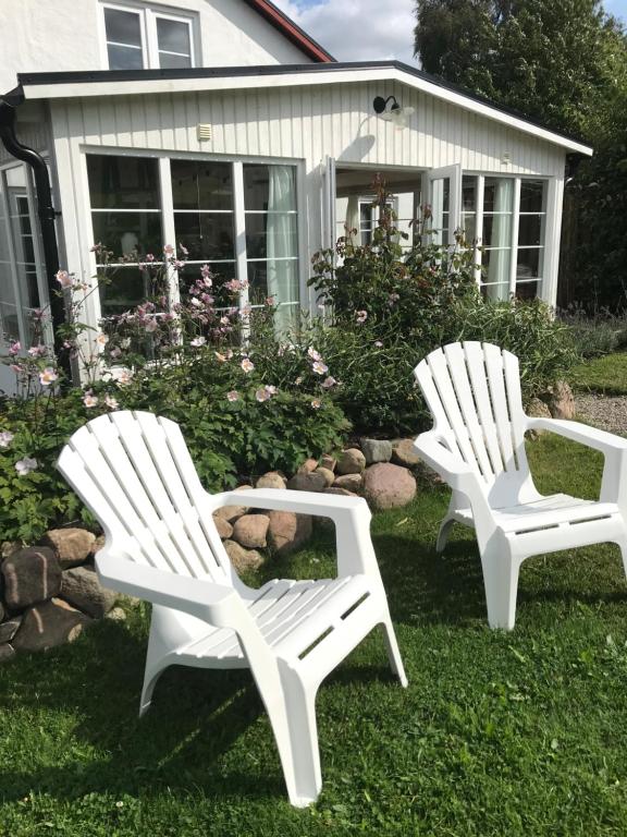 twee witte stoelen in het gras voor een huis bij Blomstertantens Hus in Trelleborg