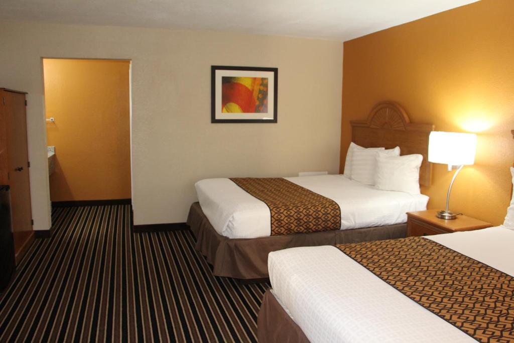 a hotel room with two beds and a lamp at Westbridge Inn & Suites in Clinton