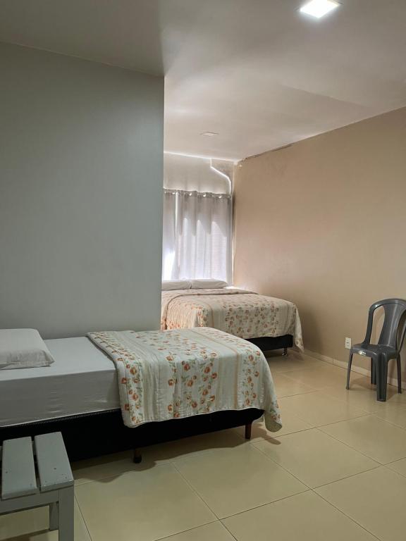 a bedroom with two beds and a chair and a window at Hotel Paraná Portal in Marechal Cândido Rondon