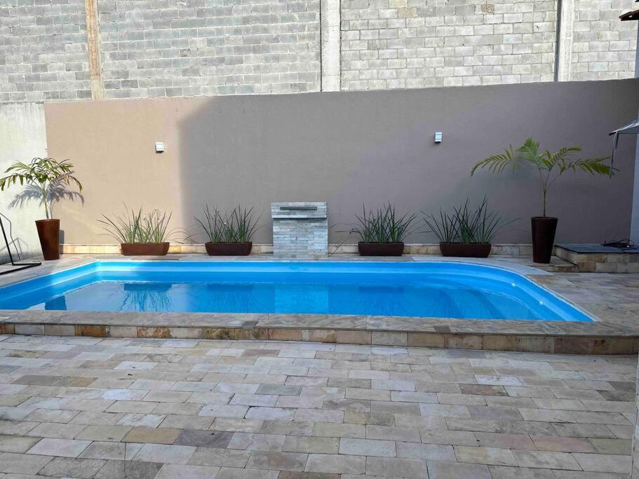 une grande piscine bleue dans une cour ornée de plantes dans l'établissement Casa Recanto dos Pássaros, à Marechal Deodoro