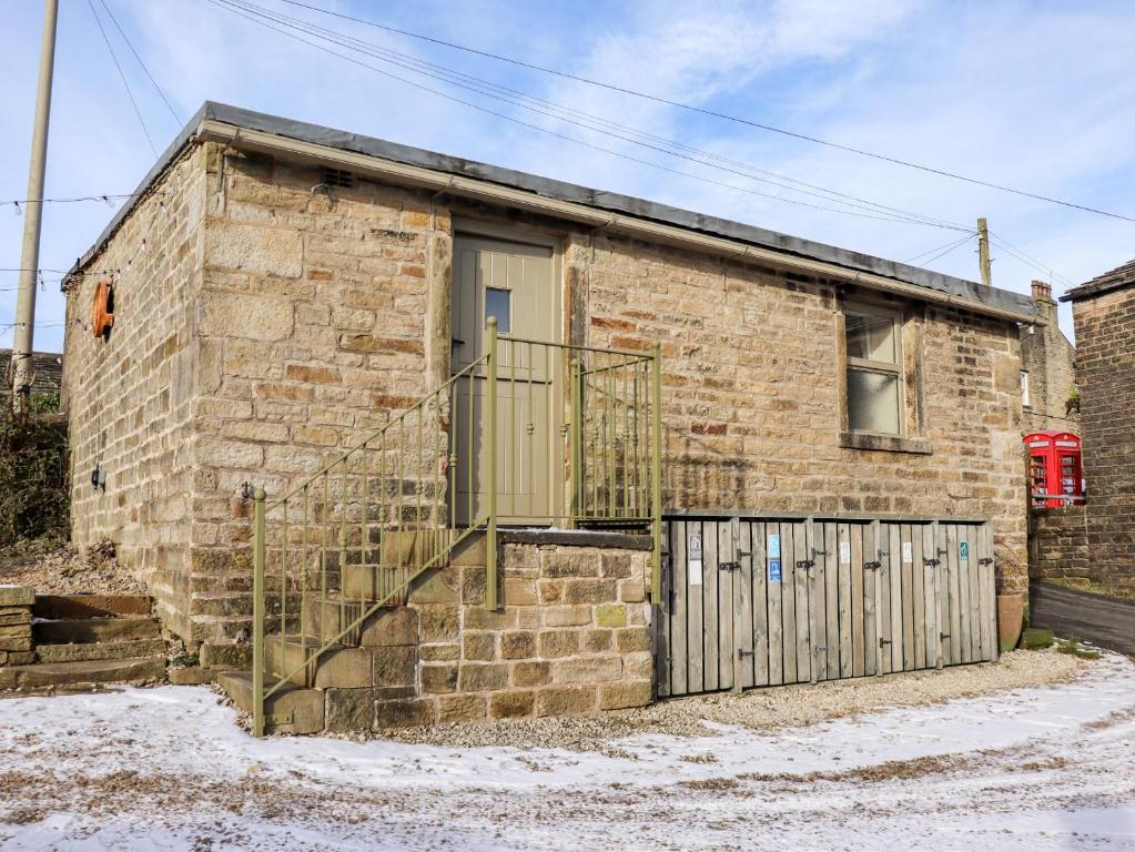 a brick building with a gate and a door at The Shearer's Hut in Holmfirth