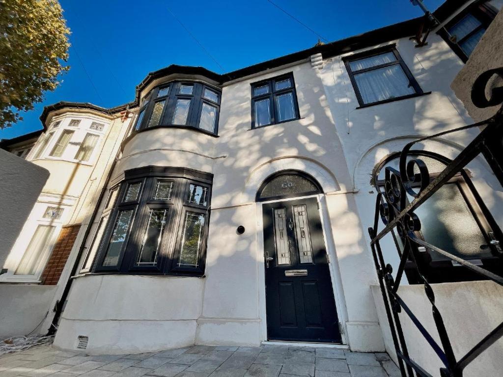 ein weißes Haus mit einer schwarzen Tür auf einer Straße in der Unterkunft Equires East London Townhouse by Harlington in London