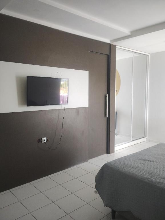 een slaapkamer met een flatscreen-tv aan de muur bij Pousada Claiô Suíte Estivas in Garanhuns