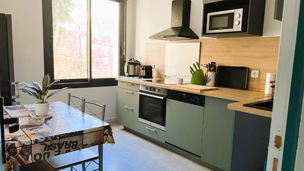ル・ブールーにあるSuperbe appartement classé 4 étoiles - le Boulouのキッチン(緑のキャビネット、テーブル付)