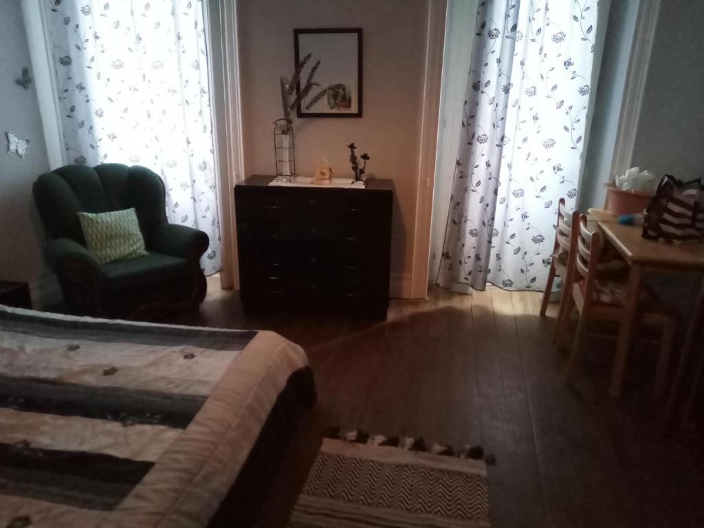 a bedroom with a bed and a chair and windows at Mary's Place in Ponta Delgada