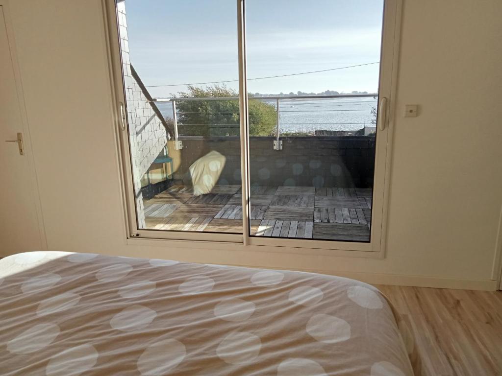 a bedroom with a large window with a view of the ocean at Parenthese relaxante les pieds dans l eau in Le Tour-du-Parc