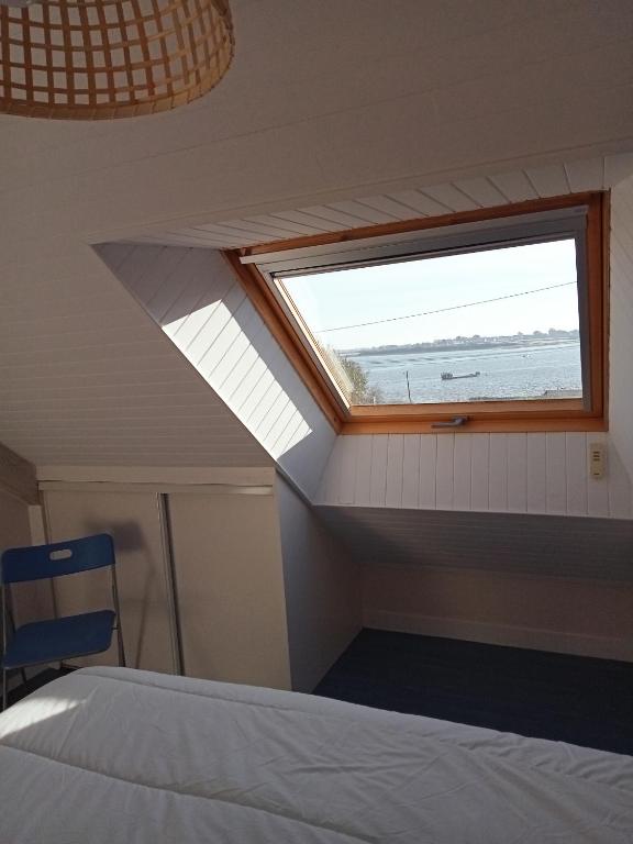 a bedroom with a window and a bed and a chair at Parenthese relaxante les pieds dans l eau in Le Tour-du-Parc