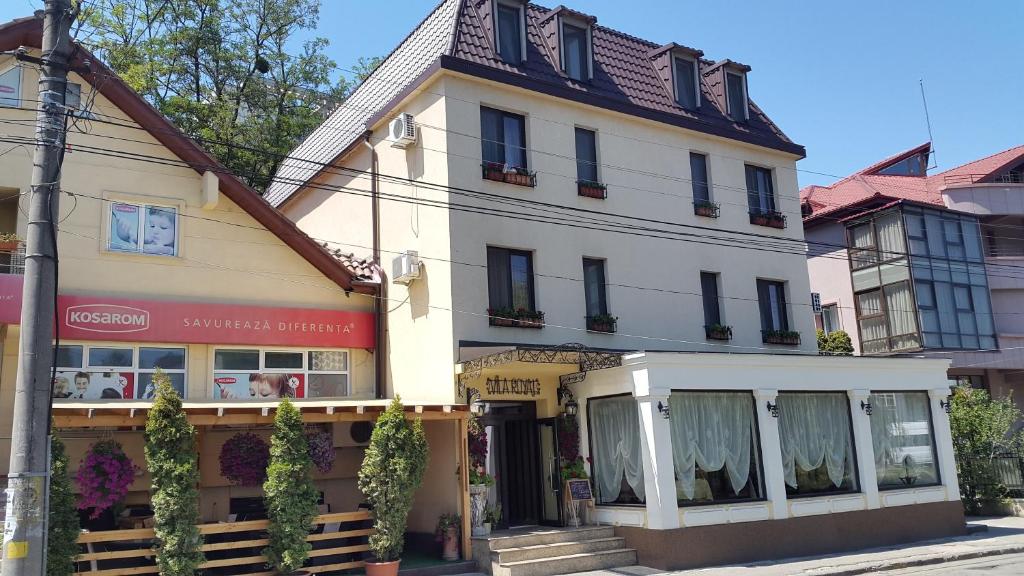 a large white building with a store in front of it at Vila Royal in Bacău