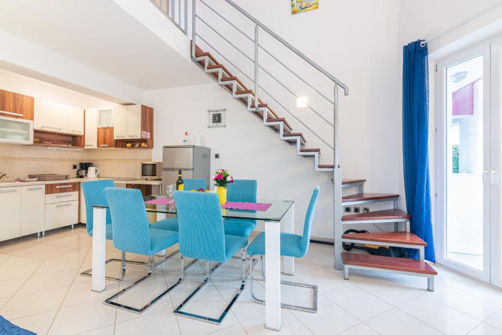a kitchen and dining room with a table and blue chairs at Apartment Ruzmarinka with Spacy Terrace in Baška