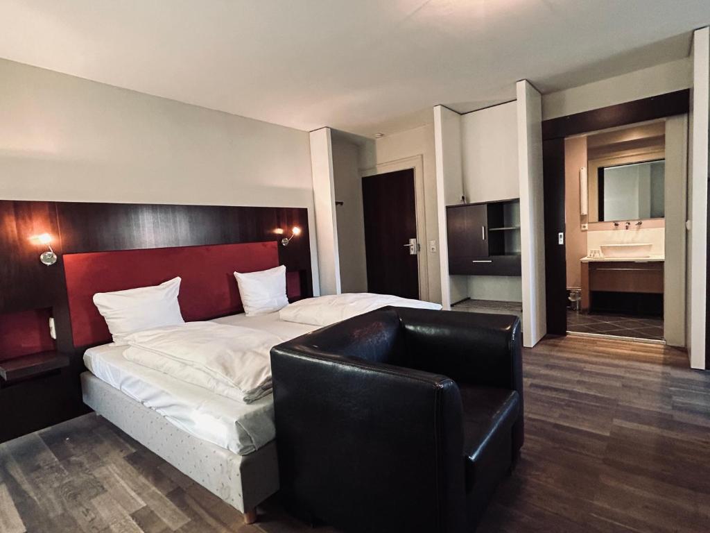 a bedroom with a large bed and a leather chair at Hotel BRASSERIE in Erlangen