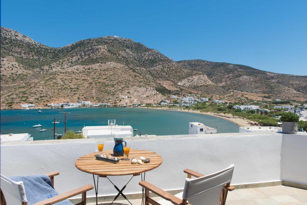 een tafel op een balkon met uitzicht op een baai bij Sifnos House - Rooms and SPA in Kamarai