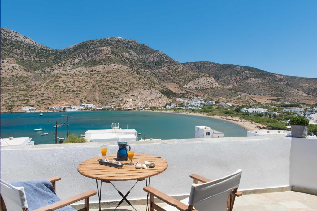 a table on a balcony with a view of a bay at Sifnos House - Rooms and SPA in Kamarai
