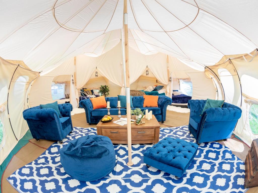 a living room with blue chairs and an umbrella at The Mahal a Majestic 4-Bedroom Glamping Palace! in Ross on Wye