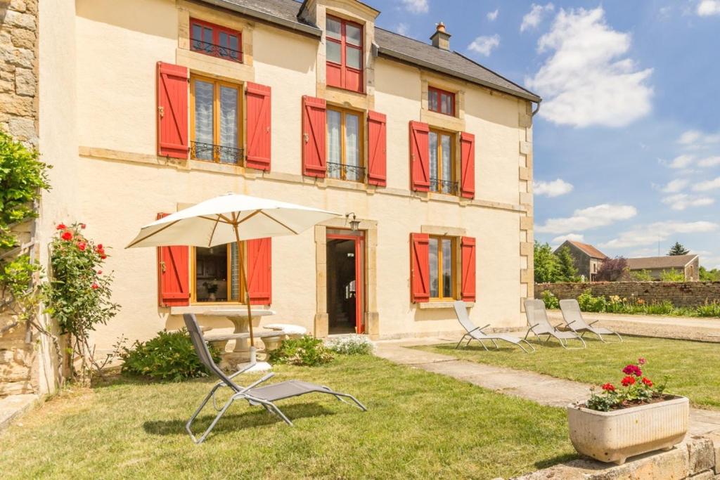 a house with chairs and an umbrella in the yard at Maison de 2 chambres avec jardin amenage et wifi a Eringes in Éringes