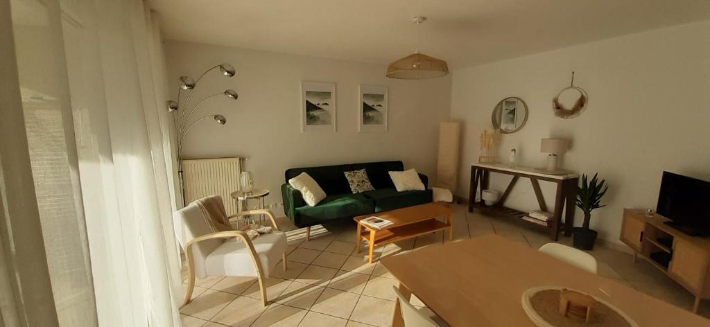 ein Wohnzimmer mit einem grünen Sofa und einem Tisch in der Unterkunft Les jardins de la Tournette, entre lac et montagnes, appartement charmant avec terrasse et jardin in Saint-Jorioz