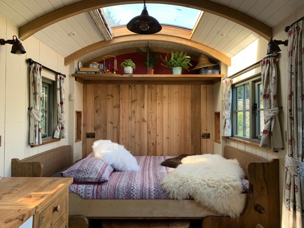 Rushford Shepherd's Hut في نيوتن أبوت: وسادتين على سرير في منزل صغير