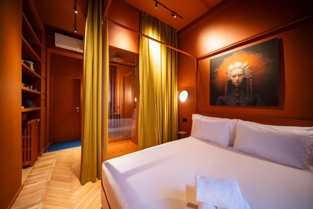 a bedroom with a white bed with a painting on the wall at Fontana 16 Rooms in Milan