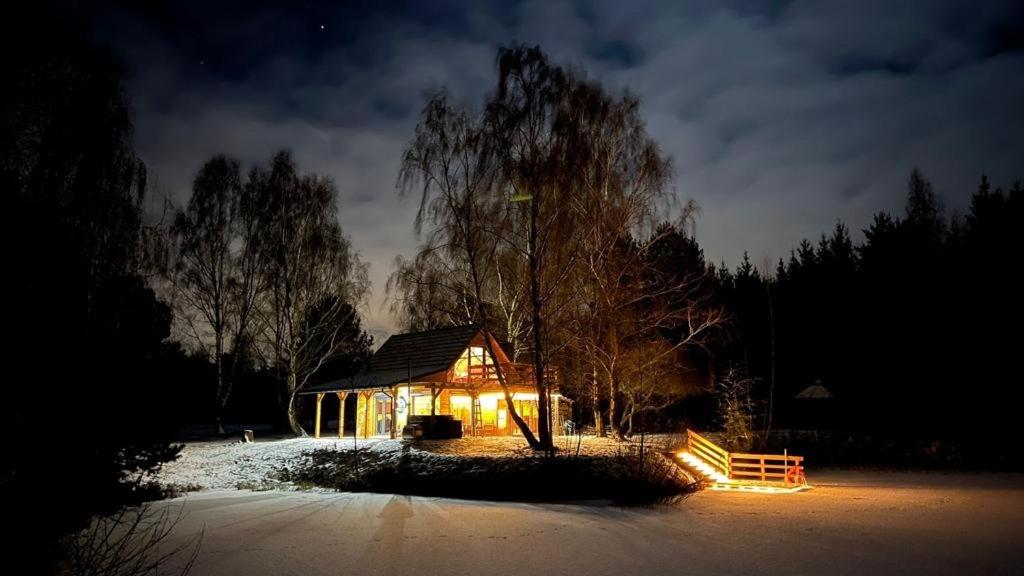 een huis met 's nachts lichten in de sneeuw bij Sauna House Smyczyna in Smyczyna