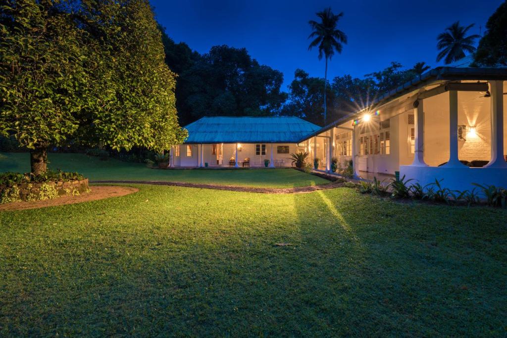 uma casa com uma árvore e um quintal à noite em Udapola Bungalow em Deraniyagala