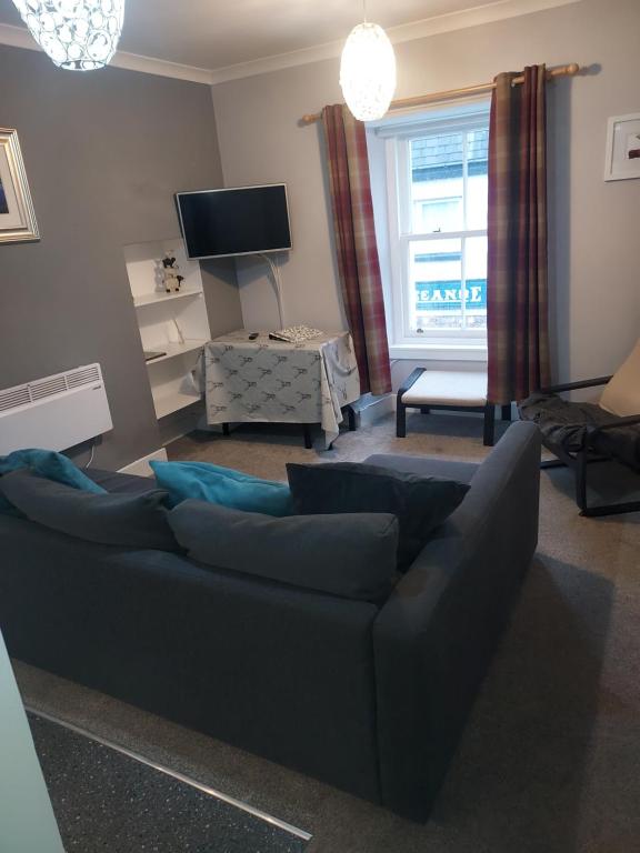 a living room with a blue couch and a tv at 4B Wentworth Street Apartment in Portree