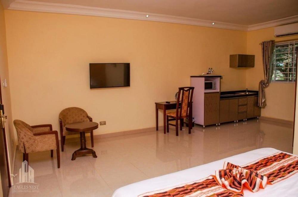 a room with a bed and a table and a kitchen at EAGLES NEST INT. HOTEL in Tarkwa