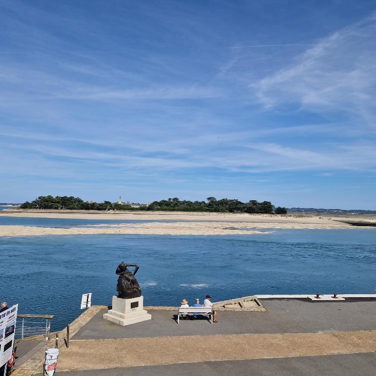 deux personnes assises sur un banc devant une statue dans l'établissement Mobilhome Piriac Sur Mer, à Piriac-sur-Mer