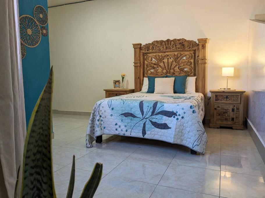ein Schlafzimmer mit einem großen Bett mit einem hölzernen Kopfteil in der Unterkunft Estudio Balandra cerca del aeropuerto SJD in San José del Cabo
