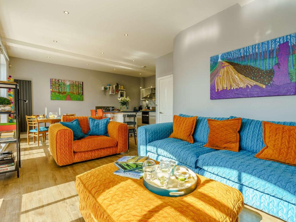 a living room with blue couches and orange chairs at 2 Bed in Ripon 83763 in Ripon