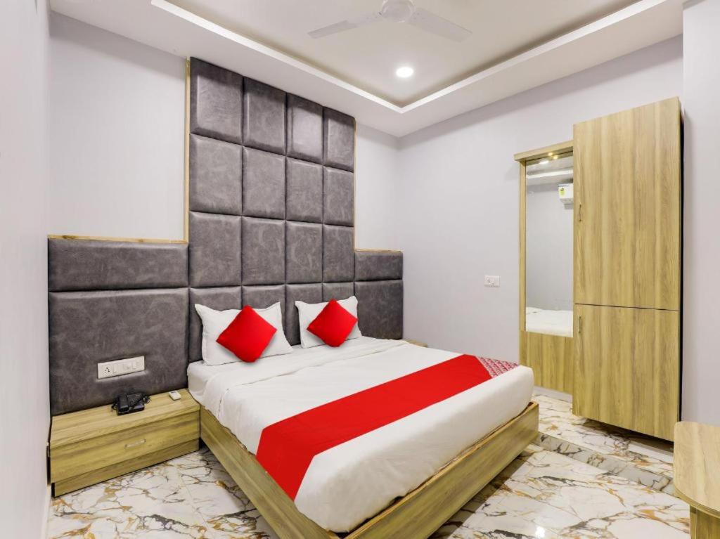 HOTEL KRISHNA في أحمد آباد: غرفة نوم بسرير كبير ومخدات حمراء