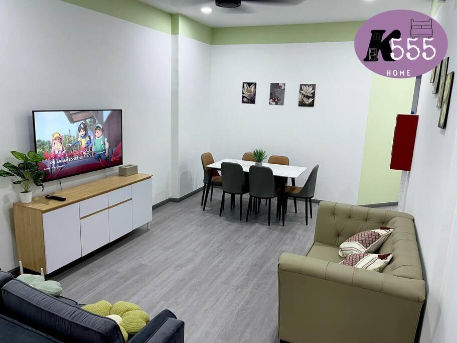 sala de estar con TV y mesa con sillas en K555 Home Stay, en Kuala Terengganu