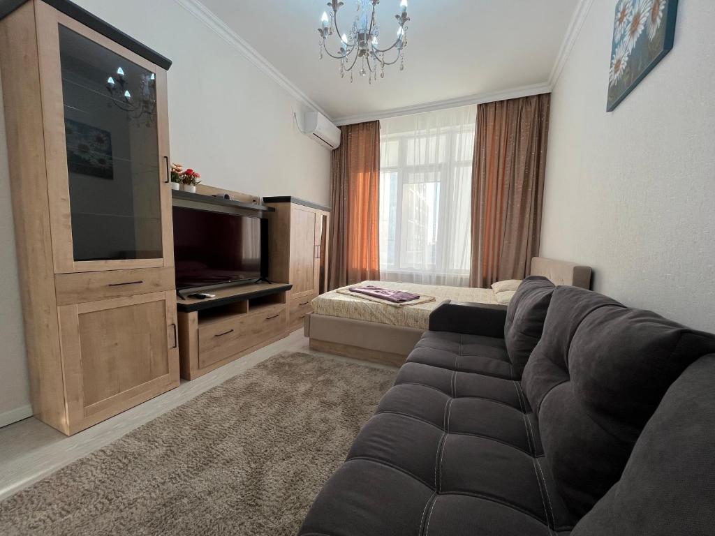 ein Wohnzimmer mit einem Sofa und einem TV in der Unterkunft Однокомнатные бизнес апартаменты в ЖК Заман in Atyrau
