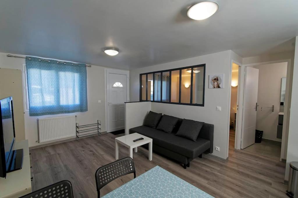 een woonkamer met een bank en een tafel bij Mon petit coin tranquille in Coubron