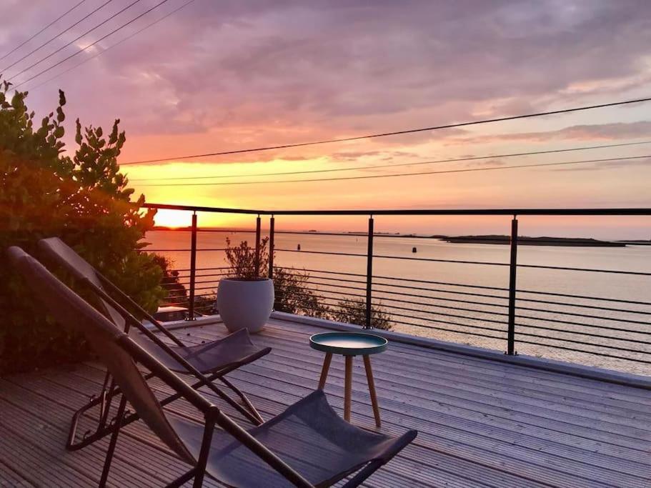 een terras met stoelen en een tafel en een zonsondergang bij Maison grande terrasse magnifique vue sur l'Aber Wrac'h in Landéda