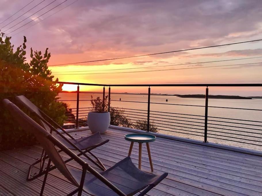 une terrasse avec des chaises, une table et un coucher de soleil dans l'établissement Maison grande terrasse magnifique vue sur l'Aber Wrac'h, à Landéda