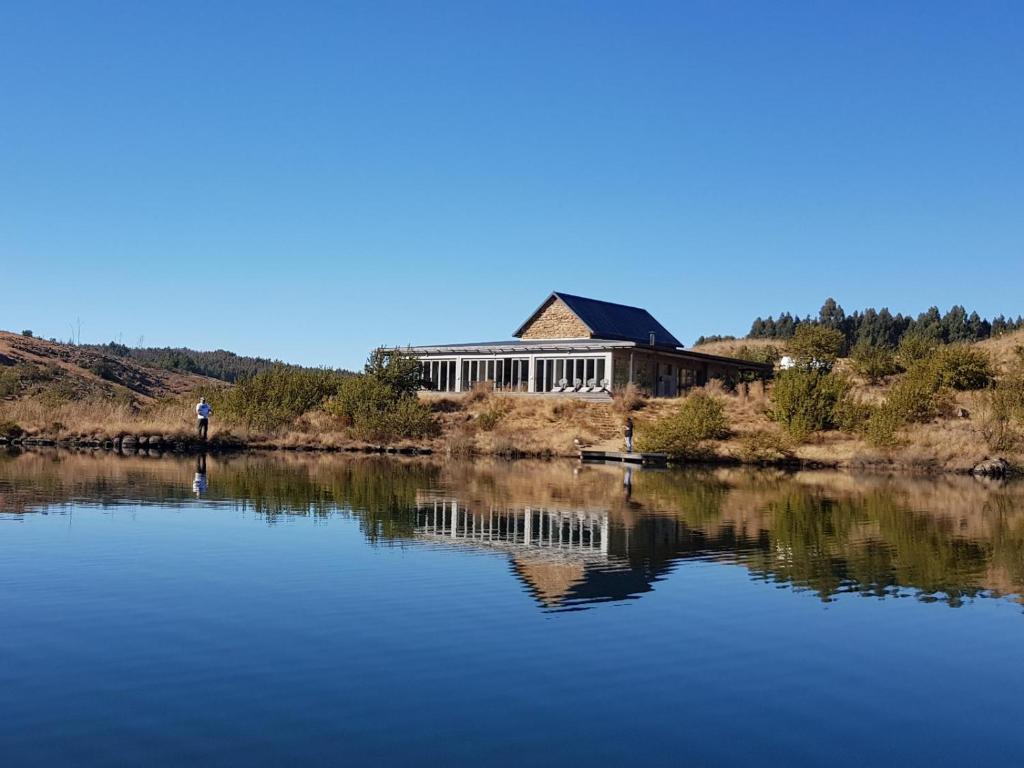 a large building sitting on the side of a lake at Star Dam Lodges in Dargle