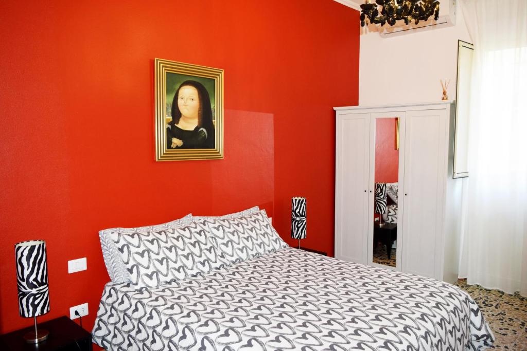 Un dormitorio rojo con una cama y un retrato de una mujer. en Affittacamere Il Pittoresco, en Cagliari