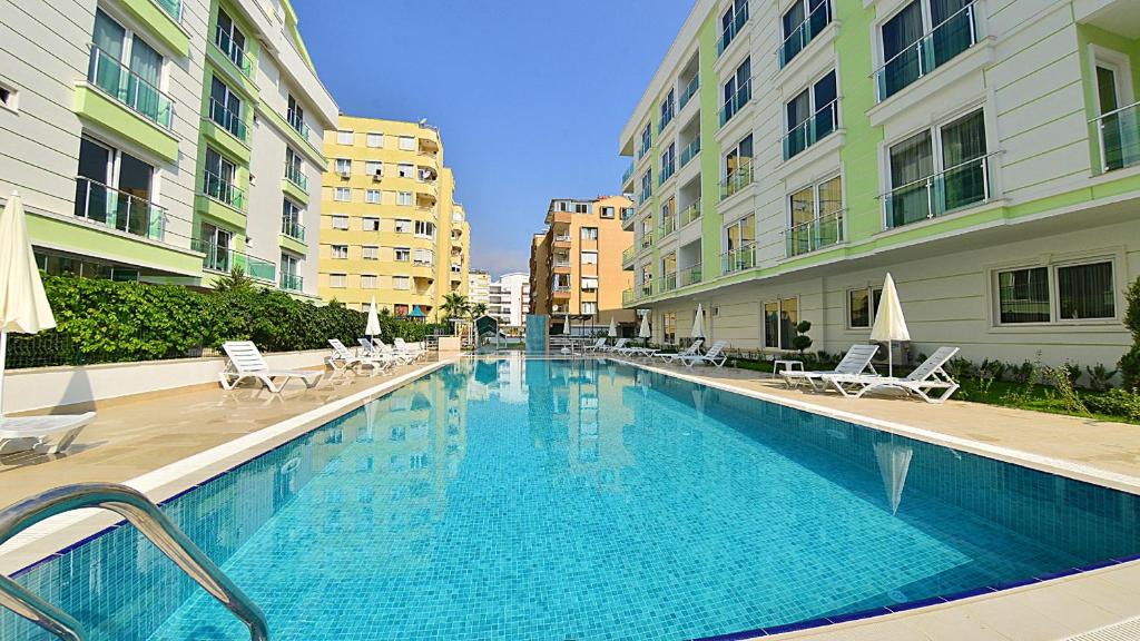 a large swimming pool with chairs and buildings at The Suites in Antalya