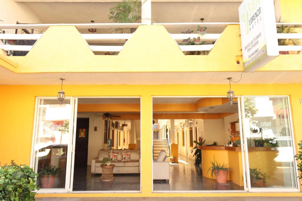 a store front with a yellow building with a balcony at Hotel San Lorenzo in Barra de Navidad
