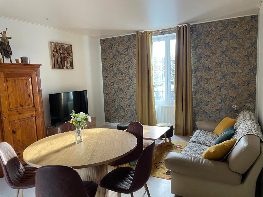 uma sala de estar com uma mesa e um sofá em Appartement Terrasse Barbizon em Barbizon
