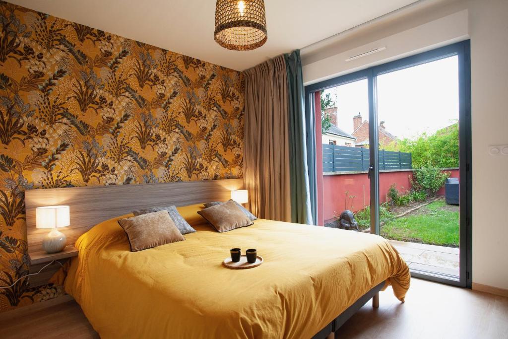 sypialnia z żółtym łóżkiem i dużym oknem w obiekcie Appartement Les Jardins de Jules Verne - Côté Jardin w Amiens