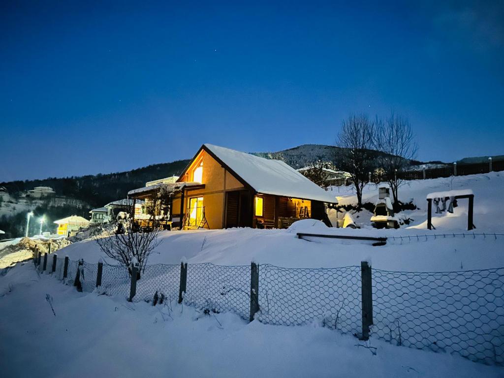 a house covered in snow in front of a fence at Log cabin in Sejdanovići