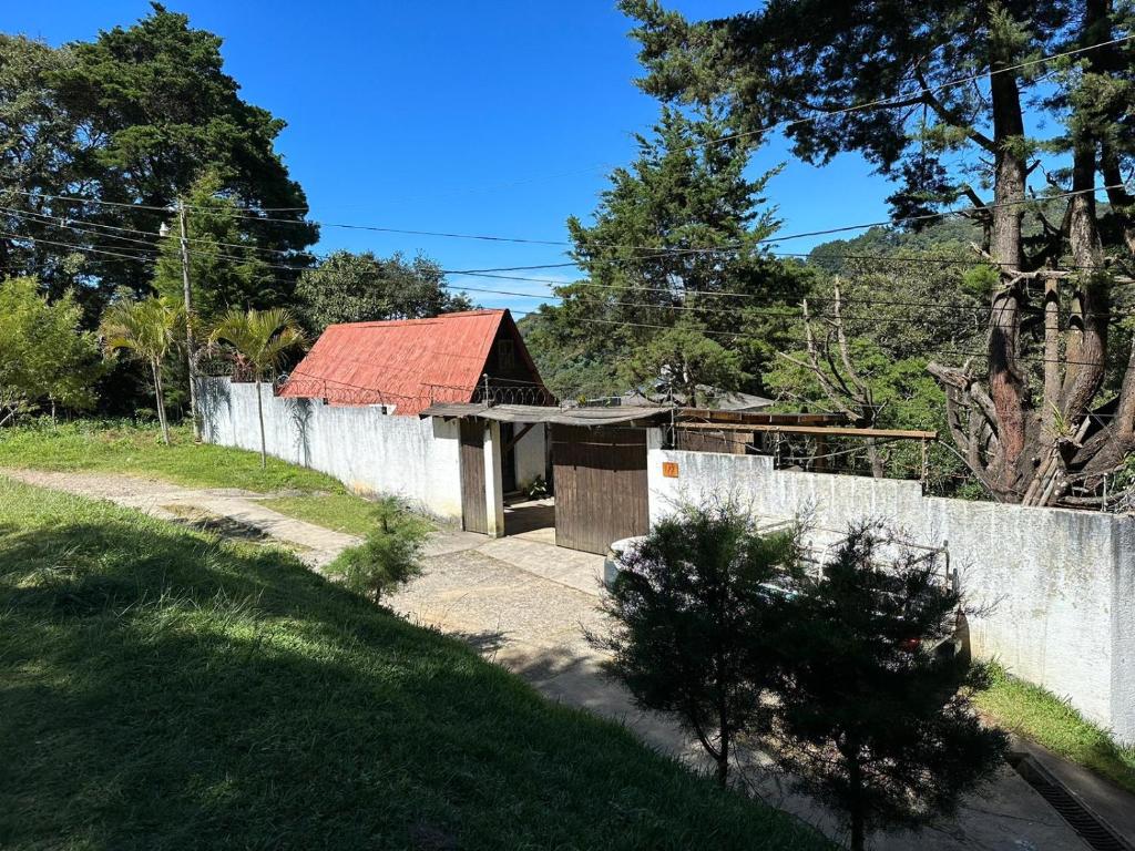 uma casa com um telhado vermelho ao lado de uma cerca em Hotel del Bosque em Guatemala