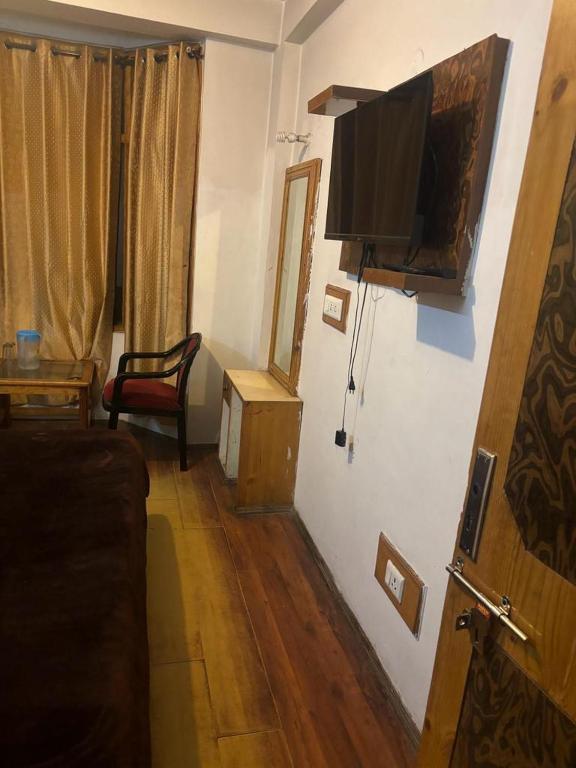 Asha Residency Shimla - Airport Road في شيملا: غرفة معيشة فيها تلفزيون على جدار