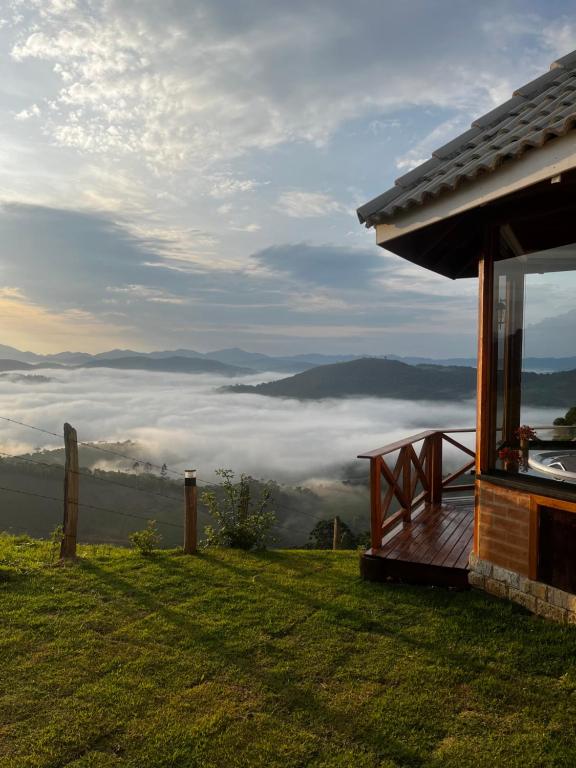una casa en una colina con vistas a las nubes en Chalé Pico da Mantiqueira en Sapucaí-Mirim