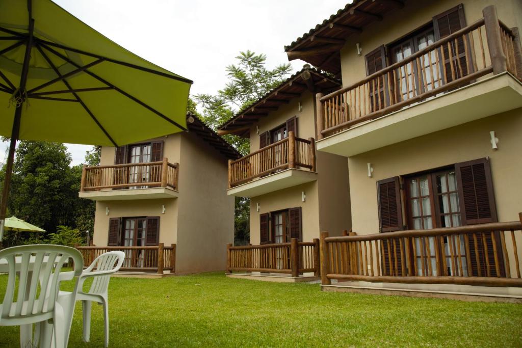 een patio met stoelen en een parasol voor een gebouw bij Vila dos Caetés - Suíte 02 - Barra do Sahy in Barra do Sahy