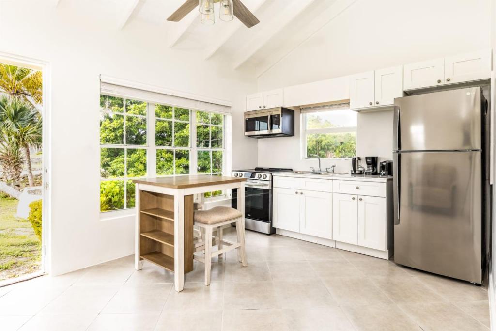 a kitchen with white cabinets and a stainless steel refrigerator at NEW Tropical Bottle Creek Stay Beach 5 min Drive in NCA