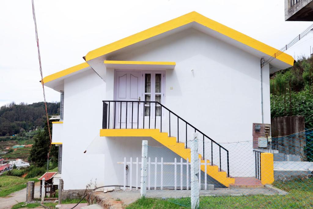 uma pequena casa branca com uma escada amarela em Seven Endue Elite em Ooty