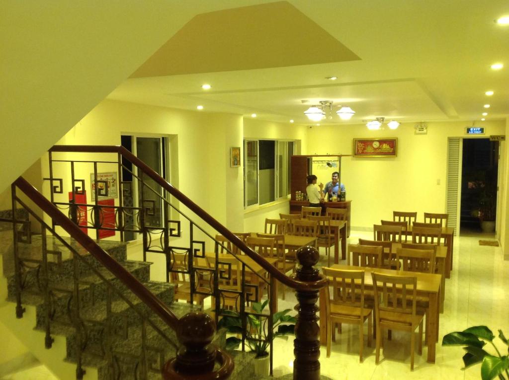 un restaurant avec des tables et des chaises en bois et un escalier dans l'établissement Hoa Vinh Hotel, à Hô-Chi-Minh-Ville