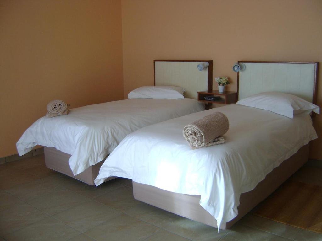 - 2 lits dans une chambre avec des draps blancs et des serviettes dans l'établissement Ochsenwagen Pension Hotel, à Rehoboth