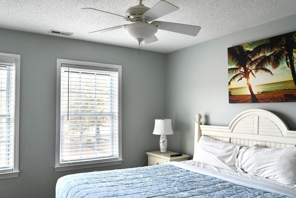 a bedroom with a bed with a ceiling fan and two windows at Spacious Home by the Beach 2# in Myrtle Beach